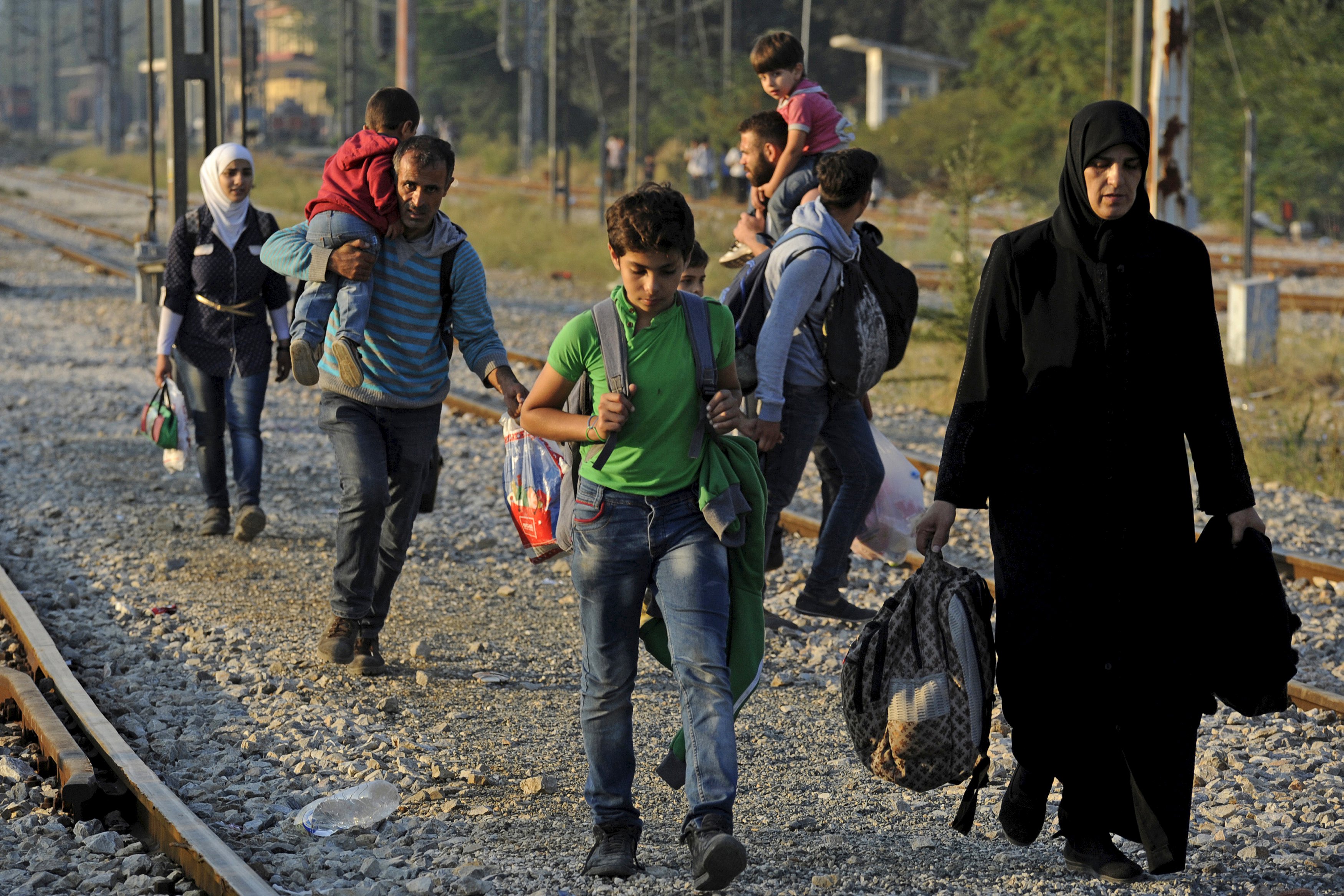 Refugees and migrants walk on railway tracks as they approach the borders of Greece with Macedonia, near the village of Idomeni