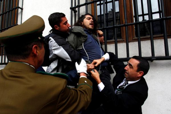 Police guards attempt to detain a chained demonstrator during a protest inside the government house against the government's education reform in Santiago, Chile, May 24, 2016. REUTERS/Stringer