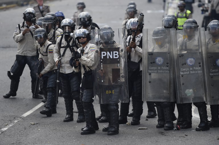 Riot police throw tear gas during clashes with demonstrators against Nicolas Maduro's government in Caracas on April 8, 2017.  The opposition is accusing pro-Maduro Supreme Court judges of attempting an internal "coup d'etat" for attempting to take over the opposition-majority legislature's powers last week. The socialist president's supporters held counter-demonstrations on Thursday, condemning Maduro's opponents as "imperialists" plotting with the United States to oust him.  / AFP PHOTO / JUAN BARRETO