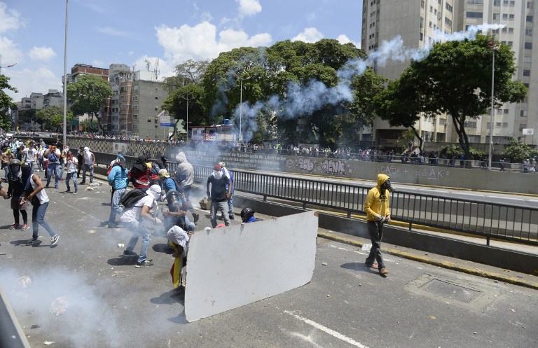 Demonstrators against Nicolas Maduro's government clash with riot police eastern Caracas on April 8, 2017.  The opposition is accusing pro-Maduro Supreme Court judges of attempting an internal "coup d'etat" for attempting to take over the opposition-majority legislature's powers last week. The socialist president's supporters held counter-demonstrations on Thursday, condemning Maduro's opponents as "imperialists" plotting with the United States to oust him.  / AFP PHOTO / FEDERICO PARRA