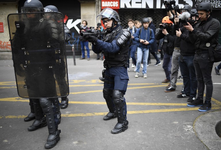 Riot police stands in a street while people take part in a demonstration called by the collectif "Front Social" and labour unions on May 8, 2017 a day after the French presidential election. / AFP PHOTO / Lionel BONAVENTURE