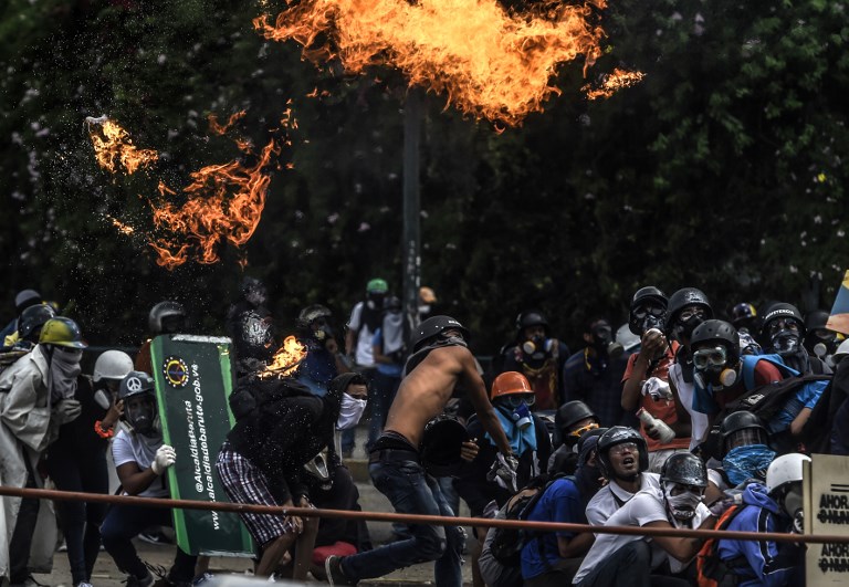 Anti-government protesters blocking the Francisco Fajardo highway in Caracas clash with riot police during a demonstration against Venezuelan President Nicolas Maduro on May 27, 2017.
Demonstrations that got underway in late March have claimed the lives of 58 people, as opposition leaders seek to ramp up pressure on Venezuela's leftist president, whose already-low popularity has cratered amid ongoing shortages of food and medicines, among other economic woes. / AFP PHOTO / JUAN BARRETO