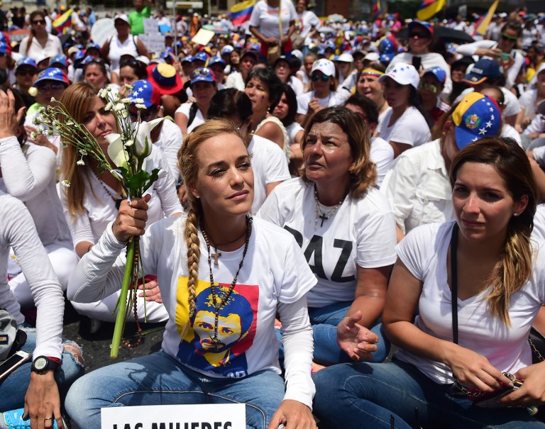 The wife of imprisoned opposition leader Leopoldo Lopez, Lilian Tintori (L), takes part in a women's march aimed to keep pressure on President Nicolas Maduro, whose authority is being increasingly challenged by protests and deadly unrest, in Caracas on May 6, 2017. The death toll since April, when the protests intensified after Maduro's administration and the courts stepped up efforts to undermine the opposition, is at least 36 according to prosecutors.  / AFP PHOTO / RONALDO SCHEMIDT