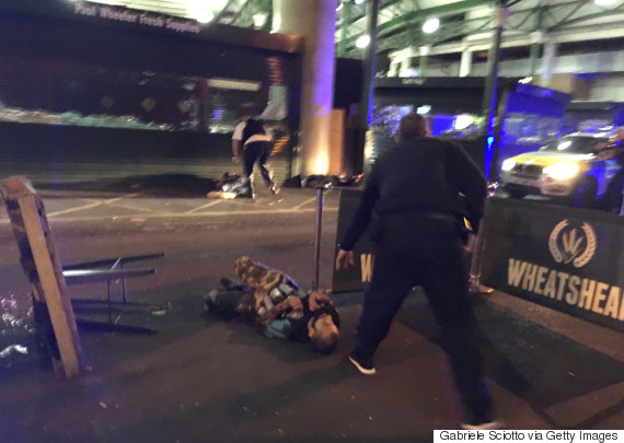 Armed police stand over what is believed to be a suspect shot at the scene of a terror attack outside Borough Market in central London on June 3, 2017. A van ploughed into pedestrians and several people were stabbed in London on Saturday, leaving at least 20 casualties in what police called a "terrorist" attack days before a general election. Armed police opened fire during two "terrorist incidents" at London Bridge and nearby Borough Market, a popular nightspot teeming with bars. / AFP PHOTO / Gabriele SCIOTTO (Photo credit should read GABRIELE SCIOTTO/AFP/Getty Images)