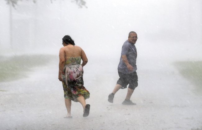 Antonio Barron, right, looks back to his girlfriend, Melissa Rocha, as they run through the street during a band of heavy rain from Hurricane Harvey Saturday, Aug. 26, 2017, in Palacios, Texas. (AP Photo/David J. Phillip)