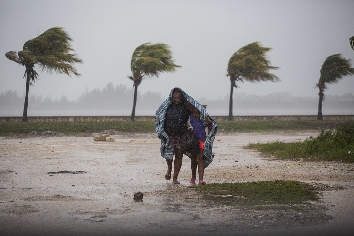 A woman and child use a blanket as protection from wind and rain as they walk in Caibarien, Cuba, Friday, Sept. 8, 2017. Hurricane Irma battered Cuba on Saturday with deafening winds and unremitting rain, pushing seawater inland and flooding homes before taking aim at Florida. Early Saturday, the hurricane center said the storm was centered about 10 miles (15 kilometers) northwest of the town of Caibarien. (AP Photo/Desmond Boylan)