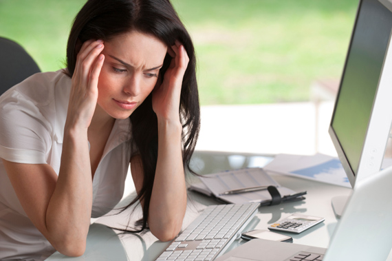 Attractive woman holding her head sitting at her desk