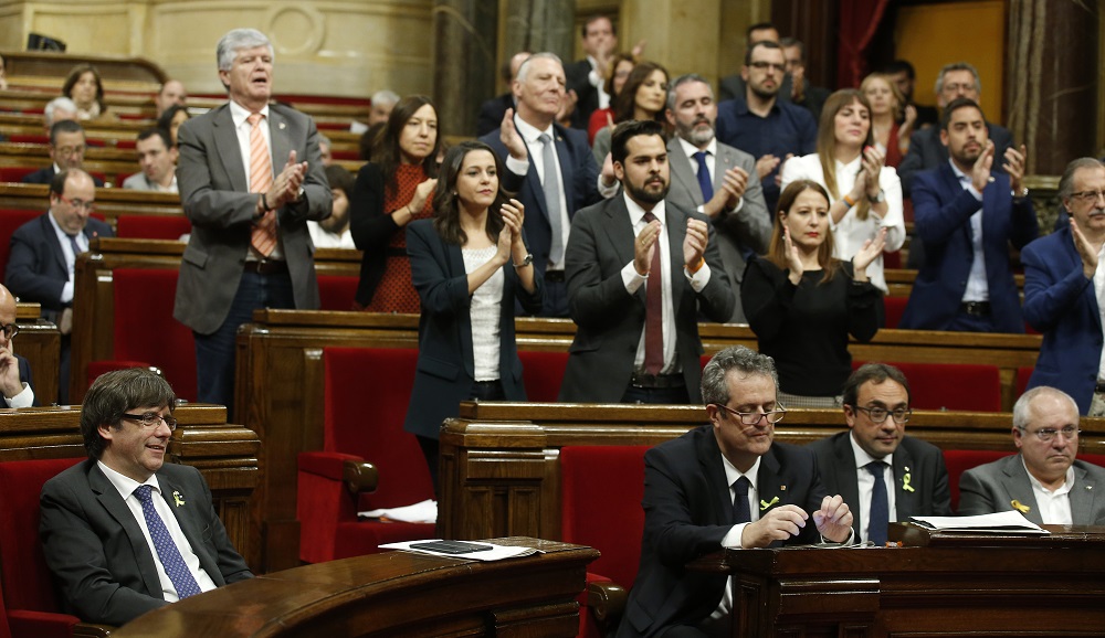 Delegates applaud after a speech as Catalan President Carles Puigdemont, bottom left, smiles during a session inside the Catalan parliament in Barcelona, Spain, Friday, Oct. 27, 2017. Catalan separatist lawmakers have filed a motion to hold a vote in the upcoming regional parliament session on whether to establish a republic independent of Spain. (AP Photo/Manu Fernandez)