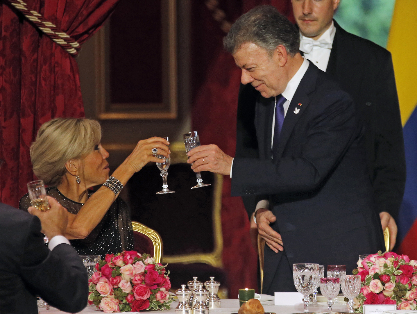 Colombian President Juan Manuel Santos (R) toasts with French President's wife Brigitte Macron during a state dinner at the Elysee Palace, in Paris, on June 21, 2017. / AFP PHOTO / POOL / JEAN-PAUL PELISSIER