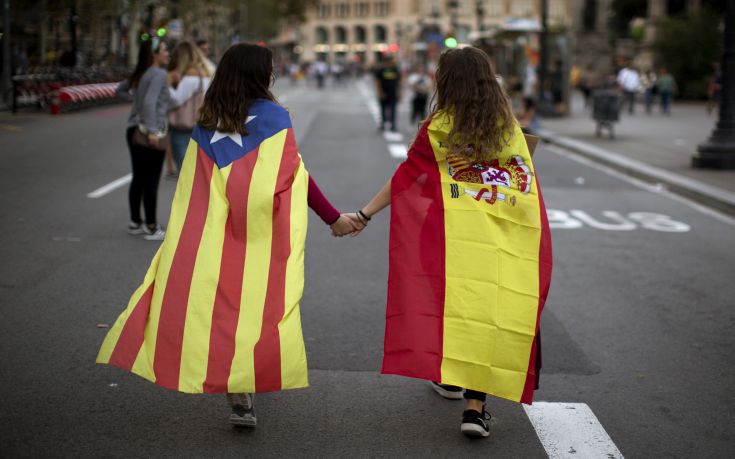 Irene Guszman, 15, wearing a Spanish flag on her shoulders and Mariona Esteve, 14, with an 'estelada' or independence flag, walk along the street to take part on a demonstration in Barcelona, Spain, Tuesday Oct.3, 2017. Thousands of people demonstrated against the confiscation of ballot boxes and charges on unarmed civilians during Sunday's referendum on Catalonia's secession from Spain that was previously declared illegal by Spain's Constitutional Court. (AP Photo/Emilio Morenatti)