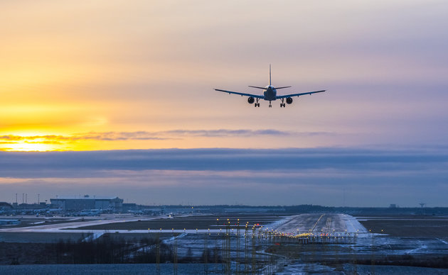 Airplane landing to airport runway in late afternoon in winter