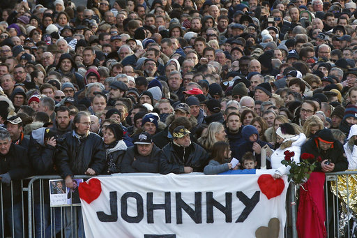 People wait outside the Madeleine church to attend French rock star Johnny Hallyday's funeral ceremony, in Paris, France, Saturday, Dec. 9, 2017. France is bidding farewell to its biggest rock star, honoring Johnny Hallyday with an exceptional funeral procession down the Champs-Elysees, a presidential speech and a motorcycle parade — all under intense security. (AP Photo/Thibault Camus)