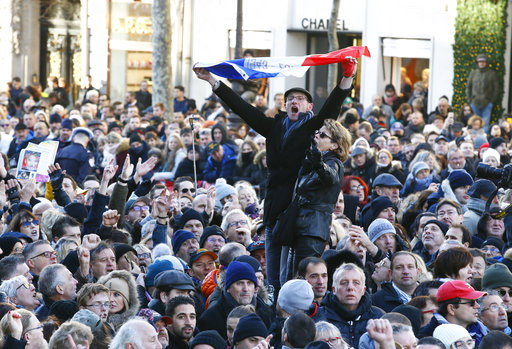 Fans sing before Johnny Hallyday's funeral ceremony in Paris, Saturday, Dec.9, 2017. France is bidding farewell to its biggest rock star, honoring Johnny Hallyday with an exceptional funeral procession down the Champs-Elysees, a presidential speech and a motorcycle parade, all under intense security. (AP Photo/Francois Mori)