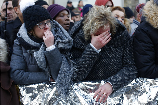 People wait outside the Madeleine church to attend Johnny Hallyday's funeral ceremony in Paris, France, Saturday, Dec. 9, 2017. France is bidding farewell to its biggest rock star, honoring Johnny Hallyday with an exceptional funeral procession down the Champs-Elysees, a presidential speech and a motorcycle parade — all under intense security. (AP Photo/Thibault Camus)