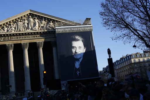 A giant poster of late French rock star Johnny Hallyday hangs on the facade of the Madeleine church, in Paris, France, Saturday, Dec. 9, 2017. France is bidding farewell to its biggest rock star, honoring Johnny Hallyday with an exceptional funeral procession down the Champs-Elysees, a presidential speech and a motorcycle parade — all under intense security. (AP Photo/Thibault Camus)