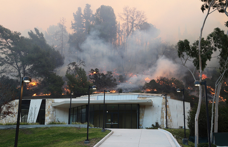 Flames from a wildfire work their way down a slope behind Leo Baeck Temple in Sepulveda Pass in the Bel Air district of Los Angeles Wednesday, Dec. 6, 2017. The temple was not damaged. (AP Photo/Reed Saxon)