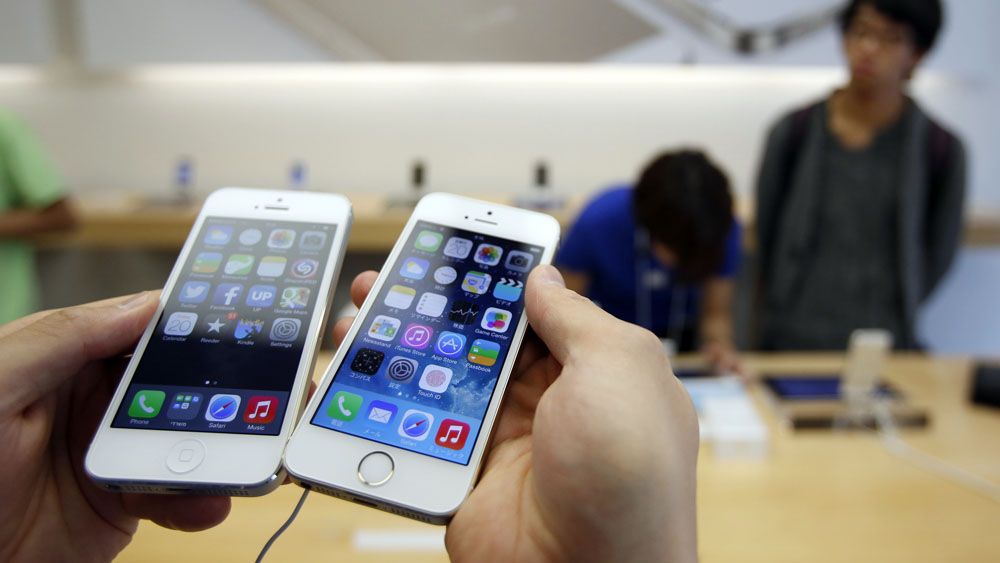 A man holds a new Apple iPhone 5S (R) next to his iPhone 5 at an Apple Store at Tokyo's Ginza shopping district September 20, 2013.   REUTERS/Toru Hanai (JAPAN - Tags: BUSINESS TELECOMS) - RTX13RW2