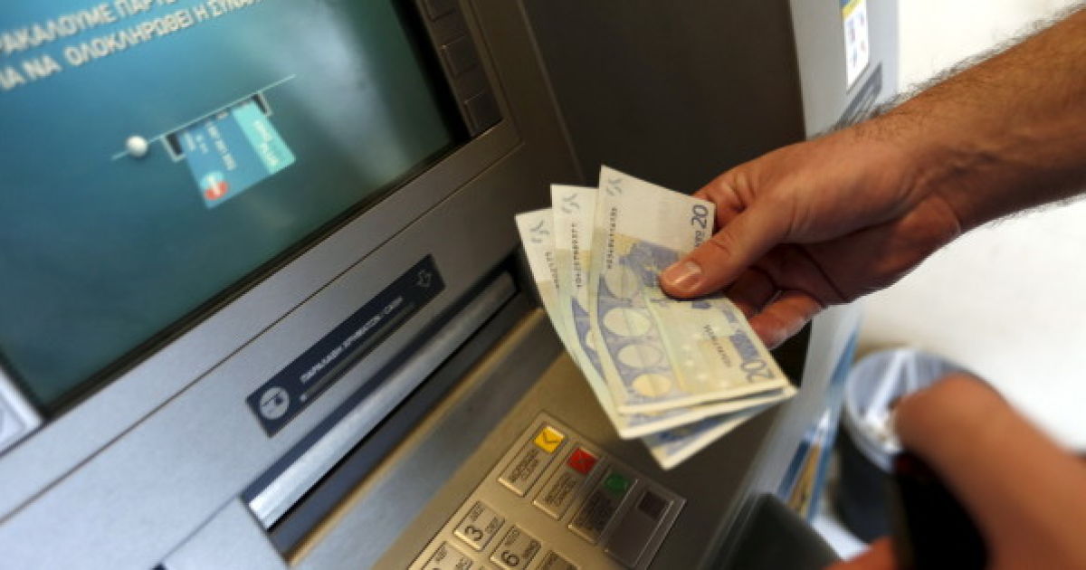 A man withdraws sixty Euros, the maximum amount allowed after the imposed capital controls in Greek banks, at a National Bank of Greece ATM in Piraeus port near Athens, Greece June 30, 2015. The head of the European Commission made a last-minute offer to try to persuade Greek Prime Minister Alexis Tsipras to accept a bailout deal he has rejected before a referendum on Sunday which EU partners say will be a choice of whether to stay in the euro. REUTERS/Yannis Behrakis