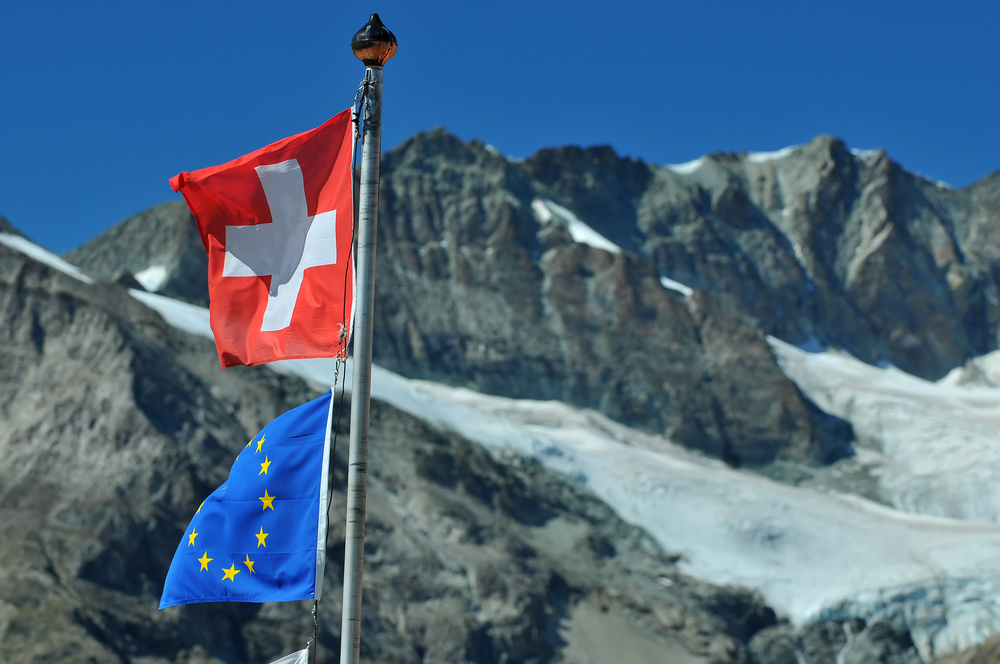 Swiss flag next to European flag. Switzerland remains independant from the european community but has promised to help financially with its problems