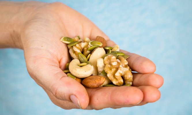 hand-holding-a-variety-of-nuts-and-seeds-picture-id499332849