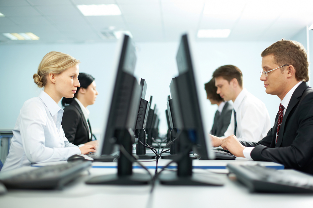 Two rows of businesspeople working on computers