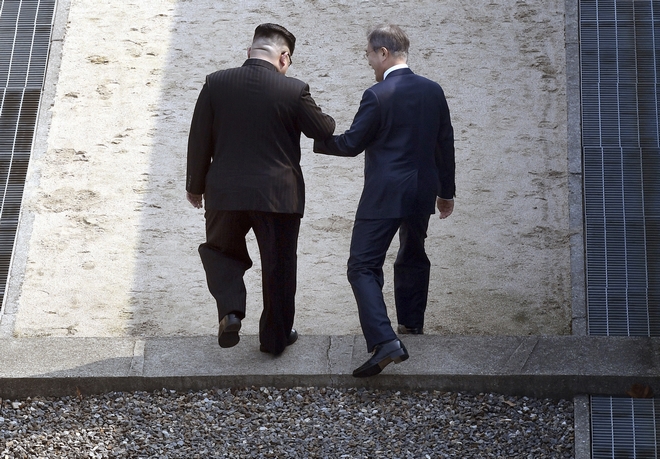 North Korean leader Kim Jong Un, left, and South Korean President Moon Jae-in cross the border line at the border village of Panmunjom in Demilitarized Zone Friday, April 27, 2018. Their discussions will be expected to focus on whether the North can be persuaded to give up its nuclear bombs. (Korea Summit Press Pool via AP)