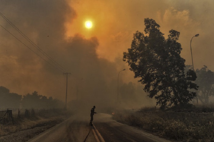 A firefighter tries to extinguish hotspots during a wildfire in Kineta, near Athens, on July 23, 2018. - More than 300 firefighters, five aircraft and two helicopters have been mobilised to tackle the "extremely difficult" situation due to strong gusts of wind, Athens fire chief Achille Tzouvaras said. (Photo by VALERIE GACHE / AFP)        (Photo credit should read VALERIE GACHE/AFP/Getty Images)