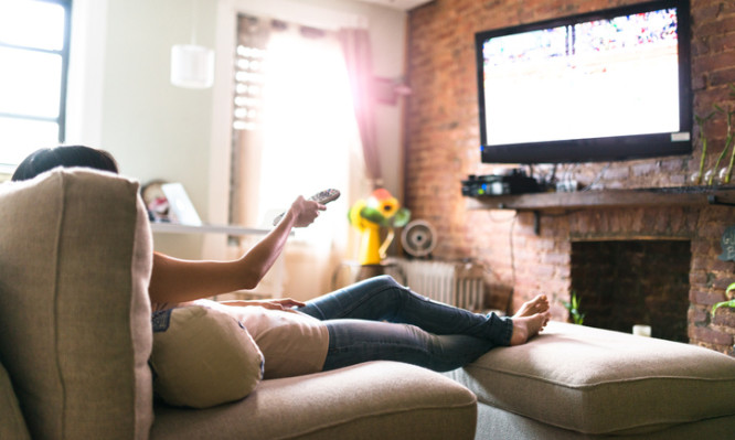 woman relaxing online on sofa reading some papers