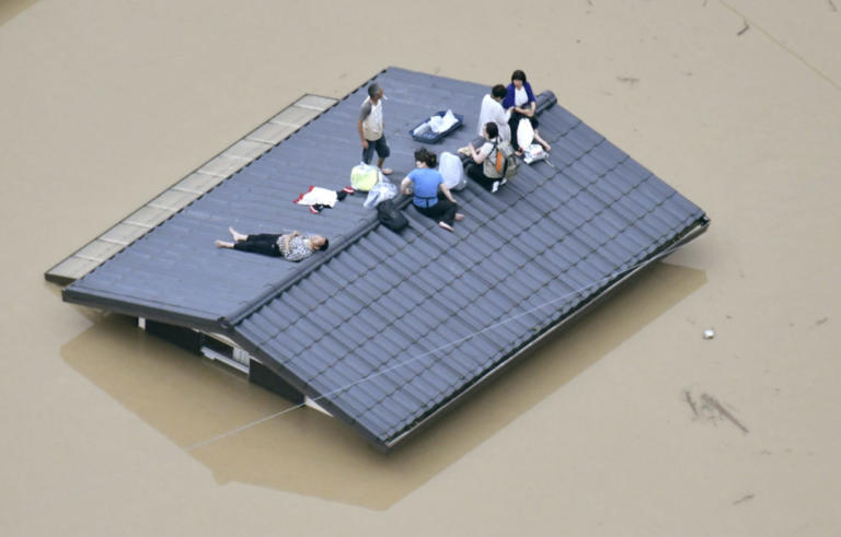 An aerial view shows local residents seen on the roof of submerged house at a flooded area as they wait for a rescue in Kurashiki, southern Japan, in this photo taken by Kyodo July 7, 2018. Mandatory credit Kyodo/via REUTERS ATTENTION EDITORS - THIS IMAGE WAS PROVIDED BY A THIRD PARTY. MANDATORY CREDIT. JAPAN OUT. NO COMMERCIAL OR EDITORIAL SALES IN JAPAN.     TPX IMAGES OF THE DAY