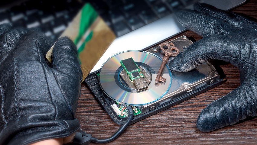 The hacker's hands in leather gloves hack into the bank's computer with a key and storage media USB flash drive