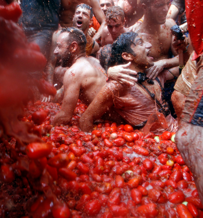 Revelers enjoy as they throw tomatoes at each other, during the annual "Tomatina", tomato fight fiesta, in the village of Bunol, 50 kilometers outside Valencia, Spain, Wednesday, Aug. 29, 2018. At the annual "Tomatina" battle, that has become a major tourist attraction, trucks dumped 160 tons of tomatoes for some 20,000 participants, many from abroad, to throw during the hour-long Wednesday morning festivities. (AP Photo/Alberto Saiz)