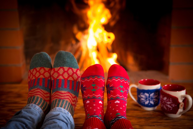 Couple relaxing at home. Feet in Christmas socks near fireplace. Winter holiday concept