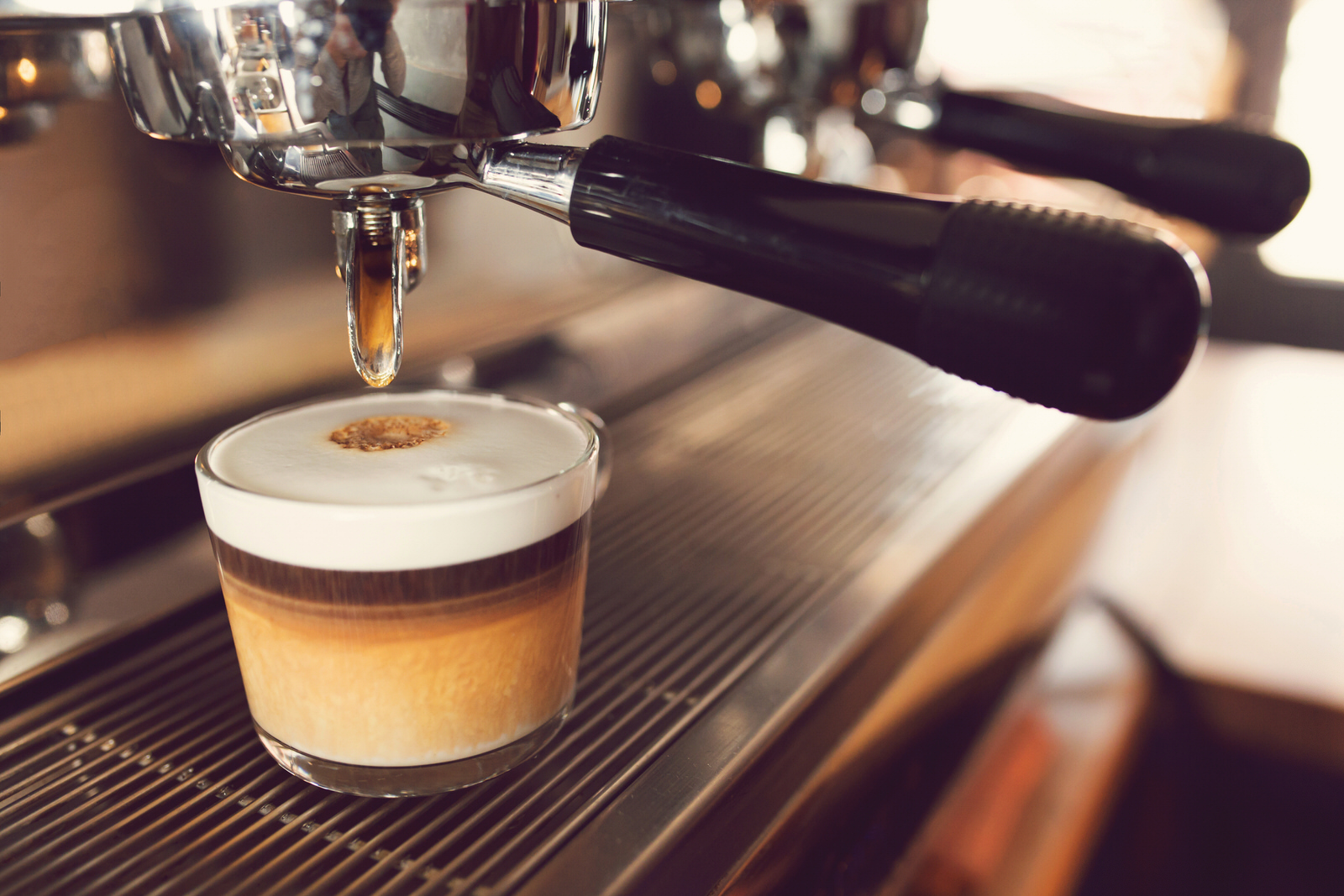 Marocchino coffee. Close-up shot of a coffee machine pouring coffee into glass.