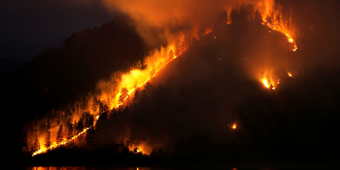 FILE PHOTO: Dry grass, bushes and trees burn on the bank of the Yenisei River in Taiga district, near Russia's Siberian city of Krasnoyarsk, April 21, 2011. Russia faces a danger of forest fires in Siberia and its far east, following blazes that ravaged thousands of hectares of land last years, Prime Minister Vladimir Putin said on Wednesday.  REUTERS/Ilya Naymushin/File Photo