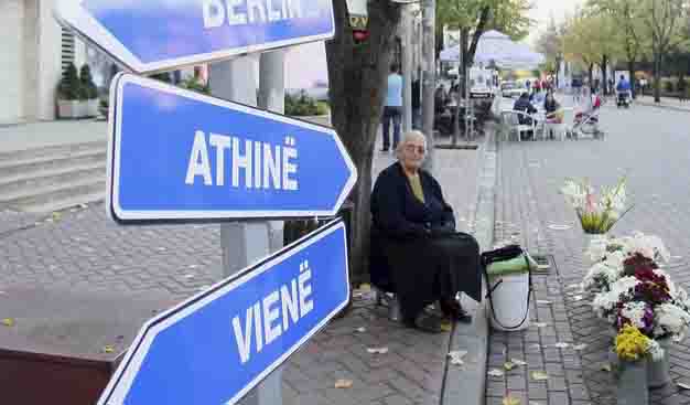 A woman sells flowers next to symbolic road signs showing Europe states under the "visa free" sign in Tirana November 7, 2010. The Council of EU interior ministers is expected to approve visa free travel for the citizens of Albania and Bosnia on November 8, 2010, a decision widely anticipated in formerly iron-clad isolated Albania.    REUTERS/Arben Celi (ALBANIA - Tags: POLITICS) - GM1E6B802LD01