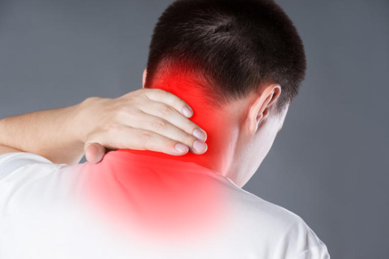 Neck pain, man suffering from backache on gray background, painful area highlighted in red