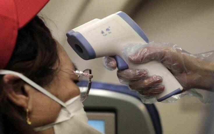 A stewardess takes the temperature of passenger as a preventive measure for the coronavirus on an Air China flight from Melbourne to Beijing before it land at Beijing Capital International Airport in China, Tuesday, Feb. 4, 2020. China said Tuesday the number of infections from a new virus surpassed 20,000 as medical workers and patients arrived at a new hospital and President Xi Jinping said "we have launched a people's war of prevention of the epidemic." (AP Photo/Andy Wong)