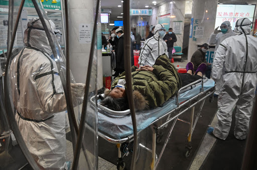 TOPSHOT - Medical staff members wearing protective clothing to help stop the spread of a deadly virus which began in the city, arrive with a patient at the Wuhan Red Cross Hospital in Wuhan on January 25, 2020. - The Chinese army deployed medical specialists on January 25 to the epicentre of a spiralling viral outbreak that has killed 41 people and spread around the world, as millions spent their normally festive Lunar New Year holiday under lockdown. (Photo by Hector RETAMAL / AFP) (Photo by HECTOR RETAMAL/AFP via Getty Images)