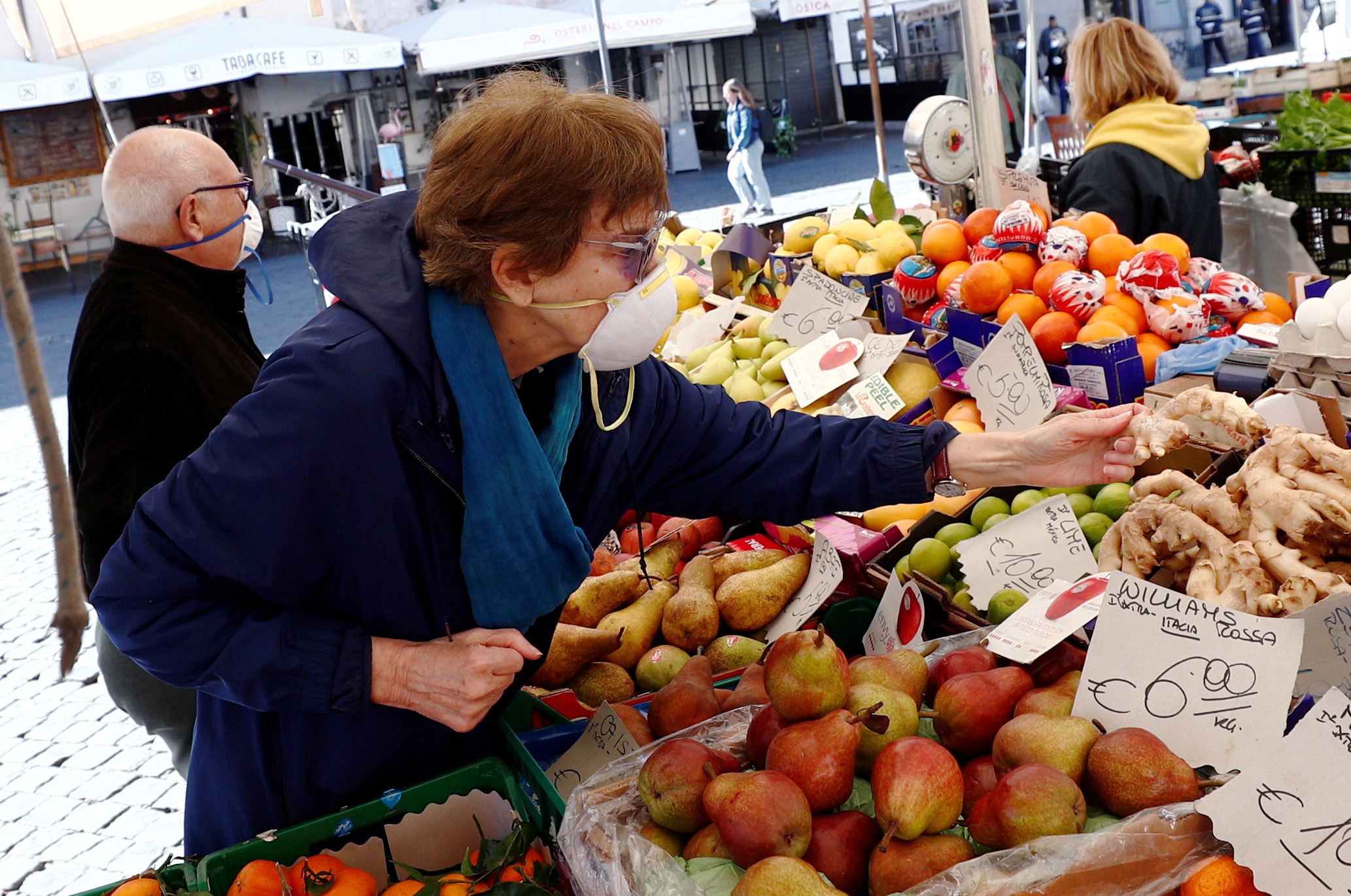 FILE PHOTO: A woman wears a protective face mask at Campo de' Fiori market on the second day of an unprecedented lockdown across all of the country, imposed to slow the outbreak of coronavirus, in Rome, Italy March 11, 2020. REUTERS/Guglielmo Mangiapane/File Photo