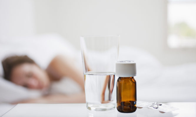 Close up of pill bottle with sick woman in background