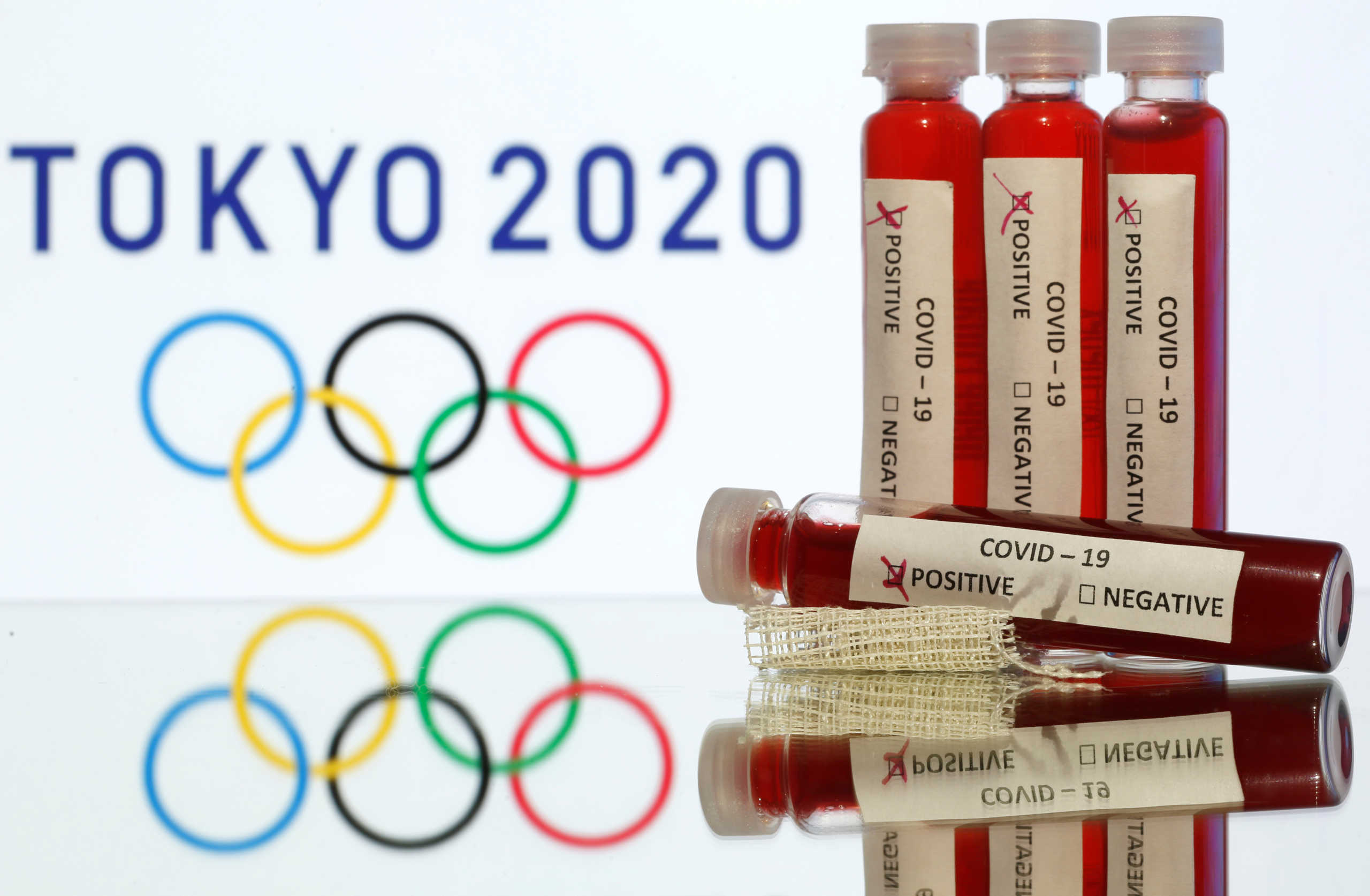 Fake blood in seen in test tubes labelled with coronavirus disease (COVID-19) in front of a displayed Tokyo 2020 Olympics logo in this illustration taken March 19, 2020. REUTERS/Dado Ruvic/Illustration