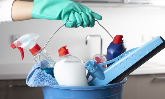 Woman holding cleaning products with glove.