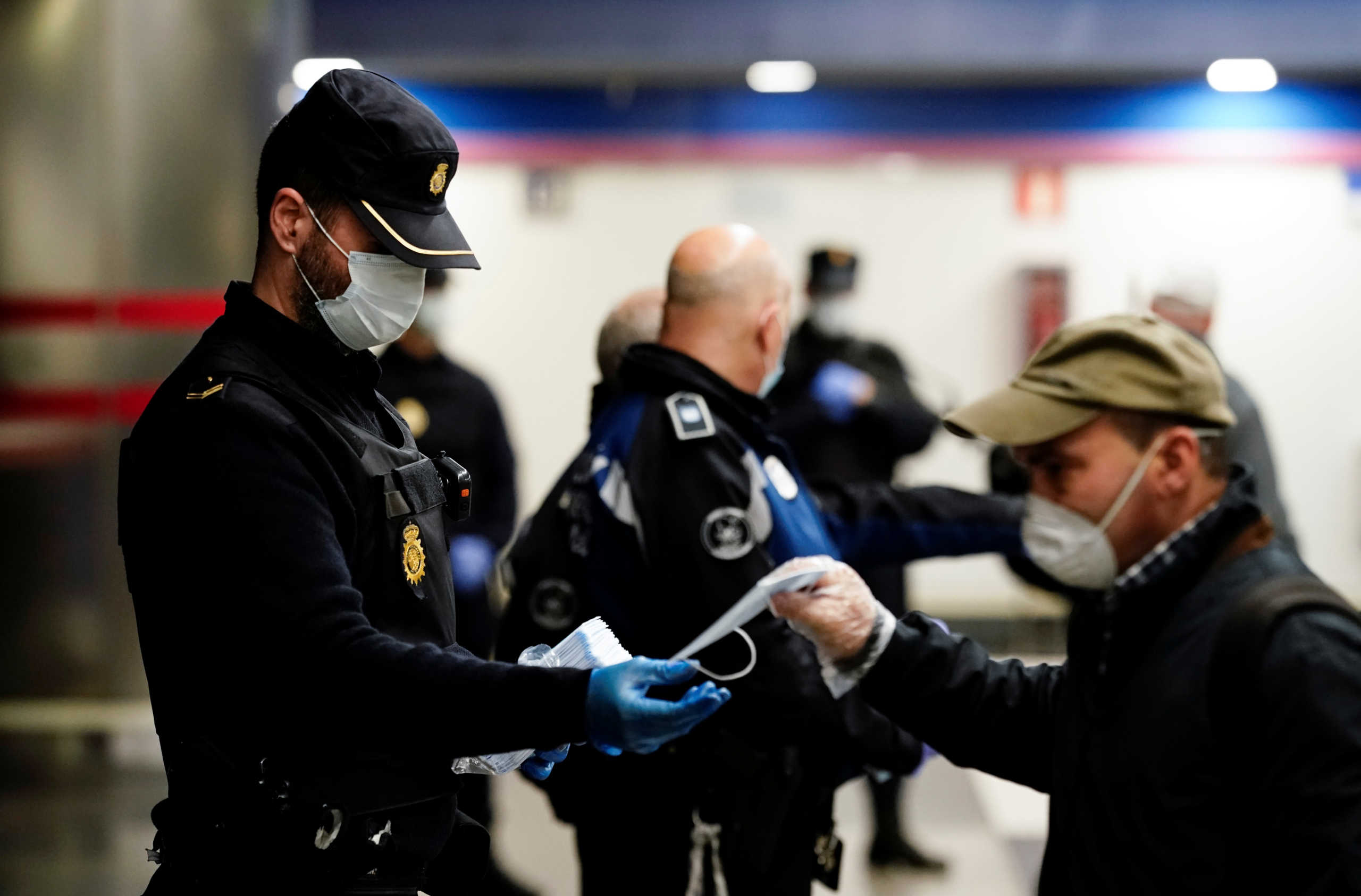 A police officer gives out free protective face masks at a metro station during the lockdown amid the coronavirus disease (COVID-19) outbreak in Madrid, Spain, April 13, 2020. REUTERS/Juan Medina