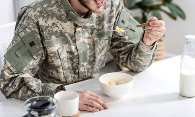 cropped view of man in camouflage uniform having breakfast in morning