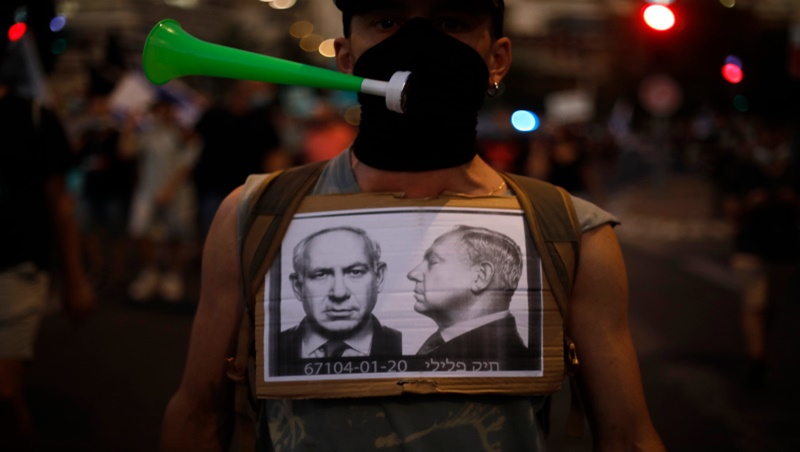 A protester wears a face mask to protect against the coronavirus during a protest against Israel's Prime Minister Benjamin Netanyahu in front of the Knesset, Israel's parliament in Jerusalem, Tuesday, July 21, 2020. (AP Photo/Ariel Schalit)