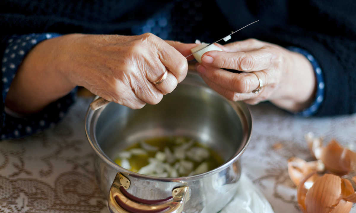 Hands of Grandma, putting onion in a pot for cooking