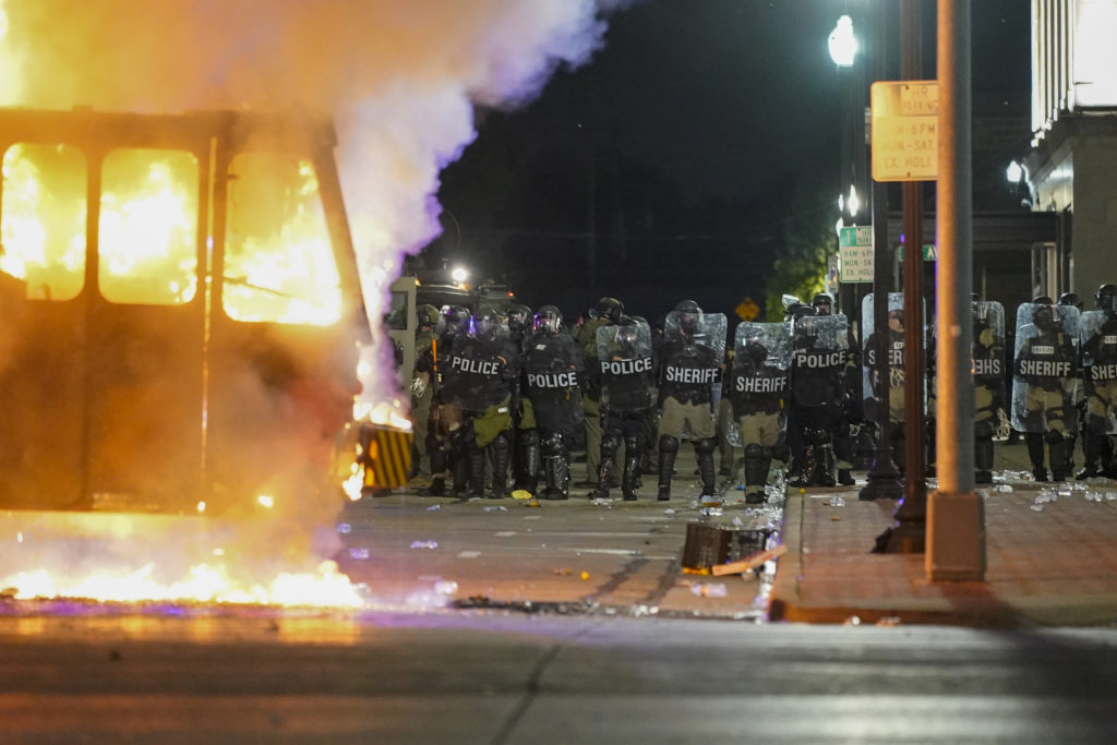 Police stand near a garbage truck ablaze during protests, Monday, Aug. 24, 2020, in Kenosha, Wis., sparked by the shooting of Jacob Blake by a Kenosha Police officer a day earlier. (AP Photo/Morry Gash)