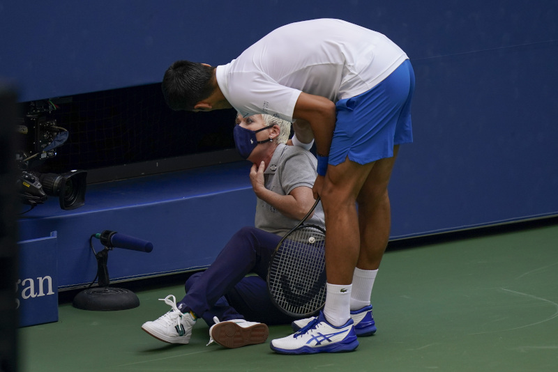 Novak Djokovic, of Serbia, checks a linesman after hitting her with a ball in reaction to losing a point to Pablo Carreno Busta, of Spain, during the fourth round of the US Open tennis championships, Sunday, Sept. 6, 2020, in New York. Djokovic defaulted the match. (AP Photo/Seth Wenig)