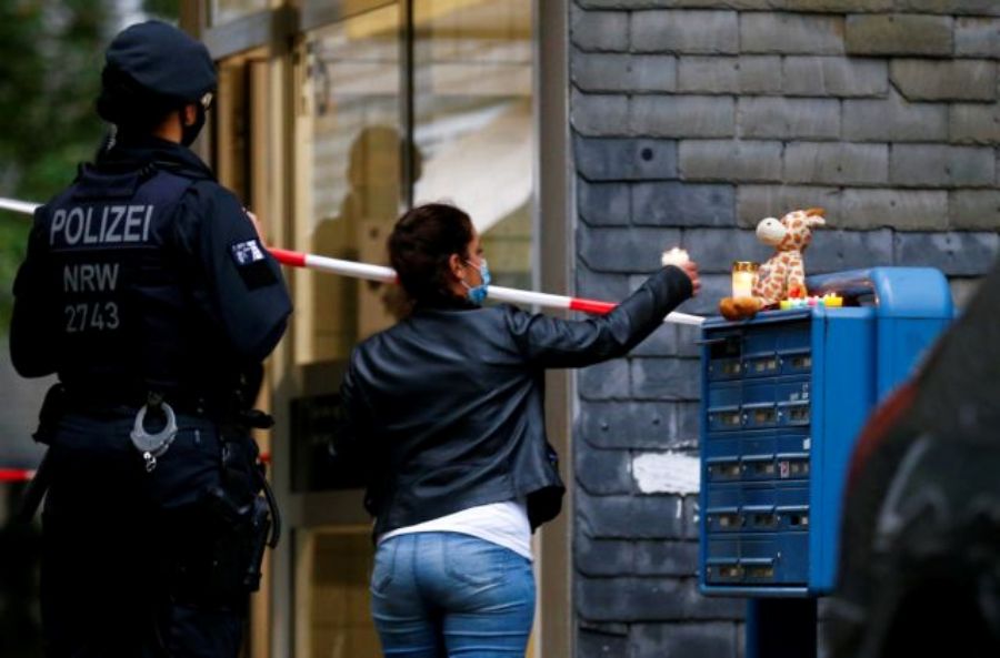 A woman places a candle outside the residential building where the bodies of five children were found in the western town of Solingen, Germany, September 3, 2020. REUTERS/Thilo Schmuelgen