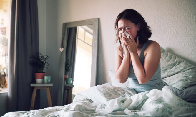 Shot of an attractive young woman suffering with the flu while sitting on her bed at home